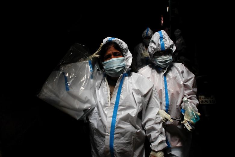 A health worker in personal protective equipment reacts as she and the rest of the team walk through an alley during a check-up campaign for the coronavirus at a slum area in Mumbai, India, August 3. REUTERS/Francis Mascarenhas
